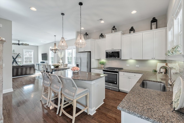 kitchen featuring appliances with stainless steel finishes, dark wood-style flooring, a center island, white cabinetry, and a sink