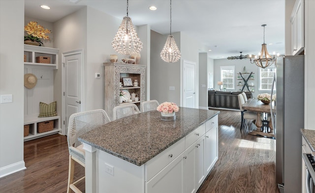 kitchen with dark stone counters, a kitchen island, white cabinetry, and a kitchen breakfast bar