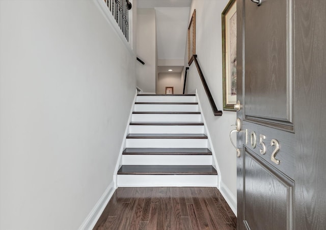 staircase with a towering ceiling, baseboards, and wood finished floors