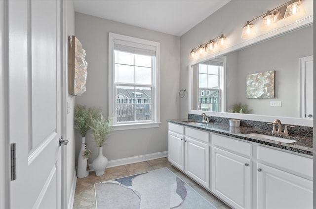 bathroom featuring double vanity, tile patterned flooring, baseboards, and a sink