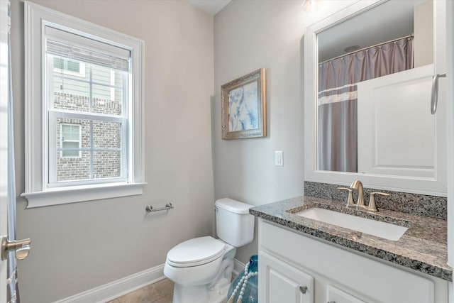 bathroom featuring a wealth of natural light, baseboards, vanity, and toilet