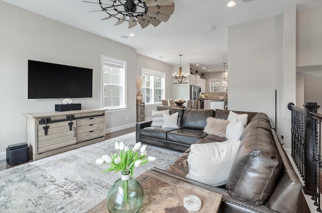 living area featuring ceiling fan with notable chandelier, baseboards, wood finished floors, and recessed lighting