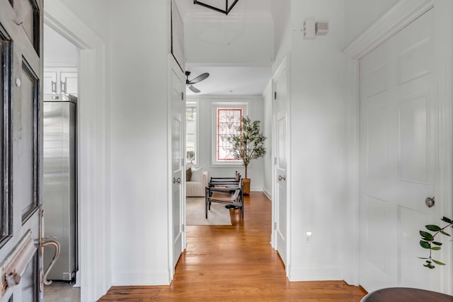 hall featuring light wood-style flooring and baseboards