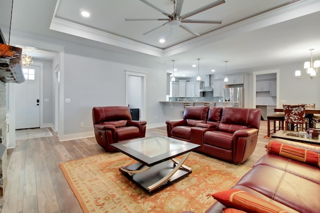 living area featuring recessed lighting, a raised ceiling, light wood-style flooring, and ceiling fan with notable chandelier