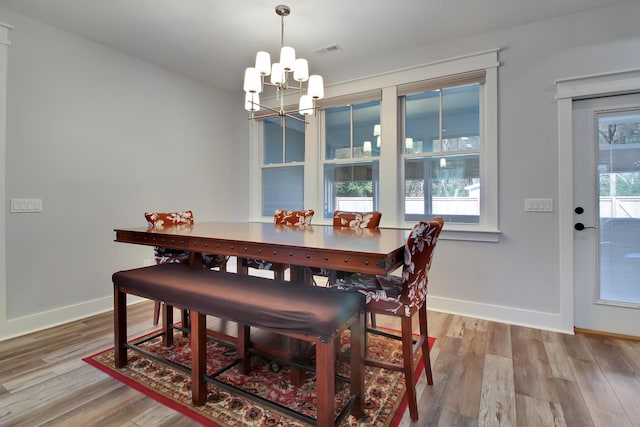 dining area with visible vents, baseboards, an inviting chandelier, and wood finished floors