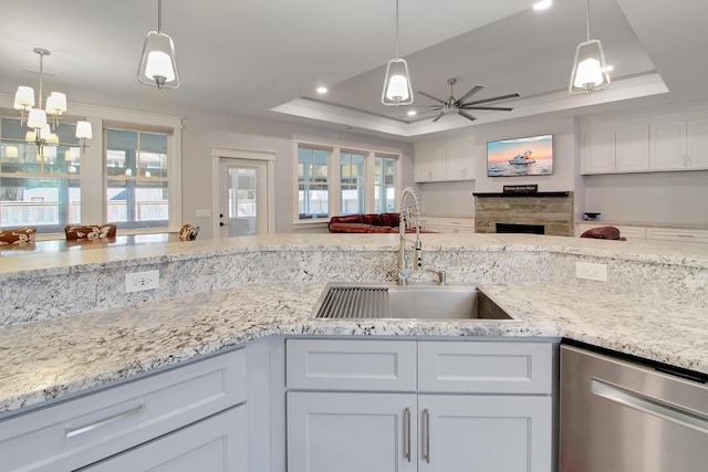 kitchen featuring a sink, open floor plan, a raised ceiling, a ceiling fan, and stainless steel dishwasher