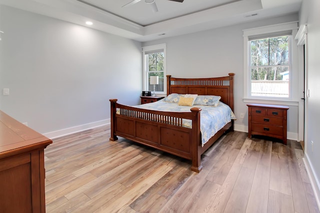 bedroom featuring visible vents, baseboards, light wood finished floors, a tray ceiling, and recessed lighting