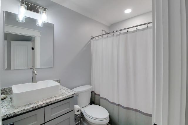 full bath featuring a shower with shower curtain, toilet, and vanity