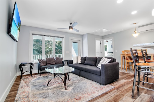 living area with baseboards, attic access, a ceiling fan, and wood finished floors