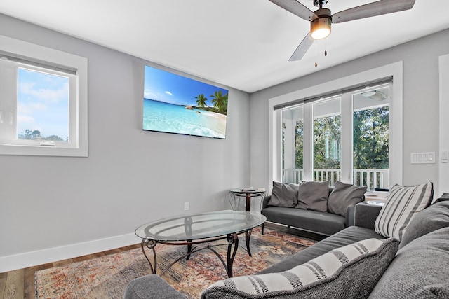 living room featuring ceiling fan, baseboards, and wood finished floors