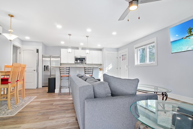 living area with recessed lighting, baseboards, light wood-type flooring, and a ceiling fan