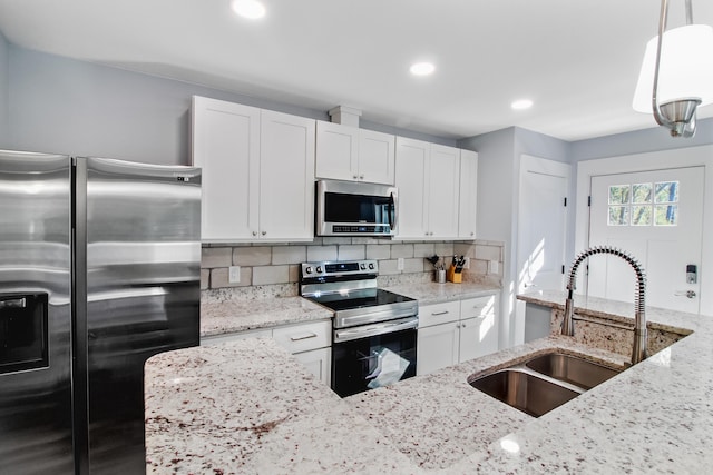 kitchen with a sink, stainless steel appliances, tasteful backsplash, and white cabinetry