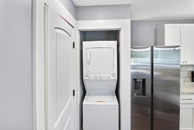 clothes washing area featuring stacked washer and dryer and laundry area