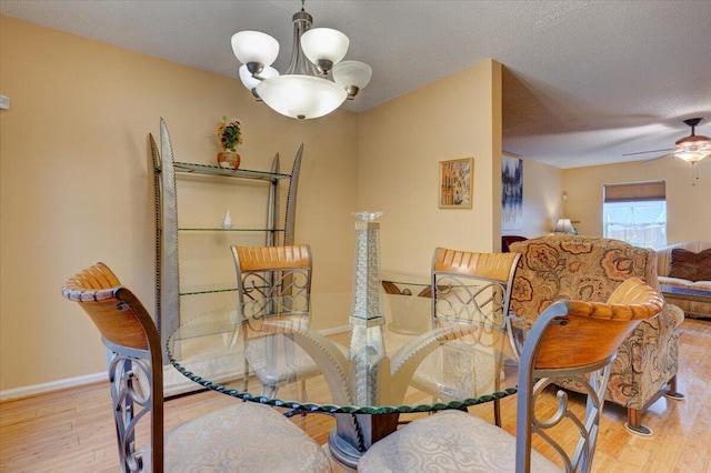 dining room featuring ceiling fan with notable chandelier, light hardwood / wood-style flooring, and a textured ceiling