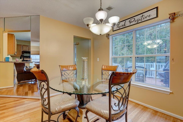 dining room featuring light wood-type flooring and an inviting chandelier