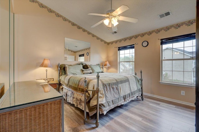 bedroom with wood-type flooring, vaulted ceiling, ceiling fan, and a textured ceiling