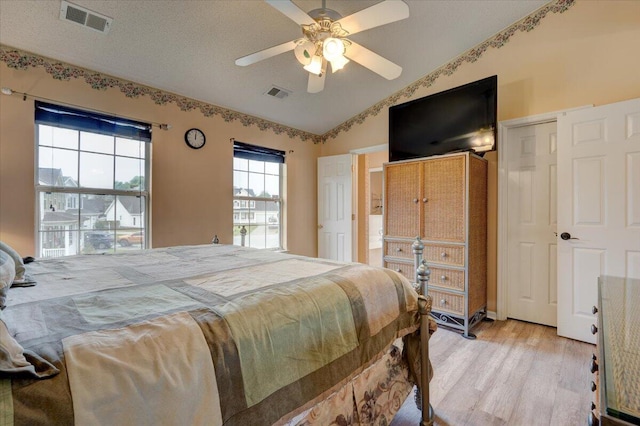 bedroom featuring a textured ceiling, light hardwood / wood-style floors, lofted ceiling, and ceiling fan