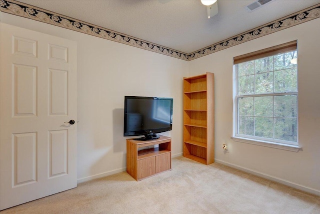 living room with a textured ceiling, light carpet, and ceiling fan