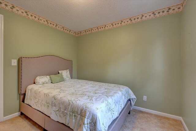 bedroom featuring a textured ceiling and light carpet