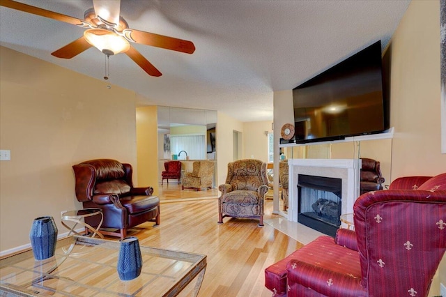 living room with hardwood / wood-style floors, ceiling fan, and a textured ceiling