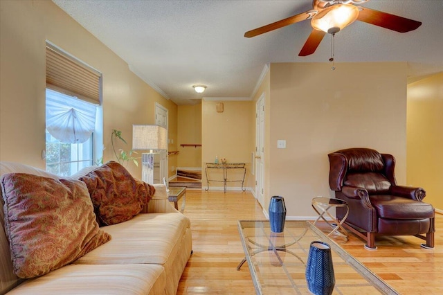 living room with ceiling fan, hardwood / wood-style floors, ornamental molding, and a textured ceiling