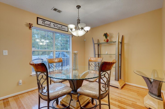 dining area featuring a textured ceiling, light wood-type flooring, and a chandelier