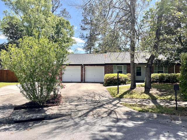 single story home featuring brick siding, an attached garage, fence, and driveway