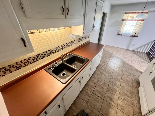 kitchen featuring decorative backsplash, a sink, white cabinets, and hanging light fixtures