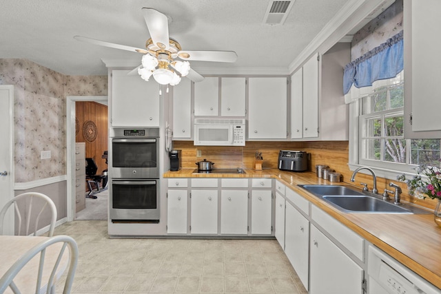 kitchen with ceiling fan, sink, a textured ceiling, white appliances, and white cabinets