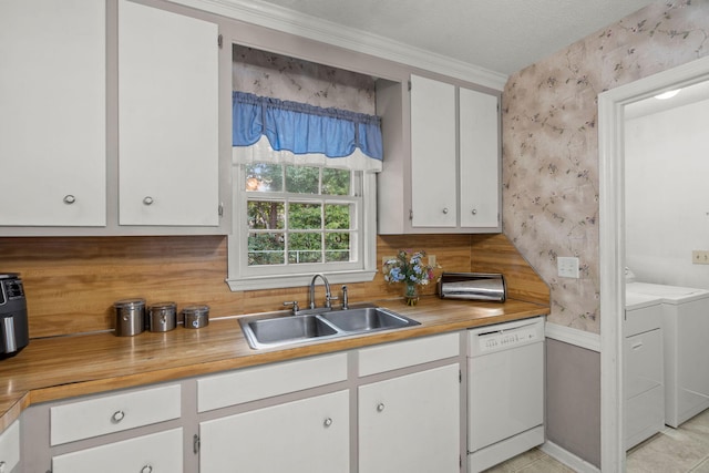 kitchen featuring white dishwasher, sink, a textured ceiling, white cabinetry, and washing machine and clothes dryer