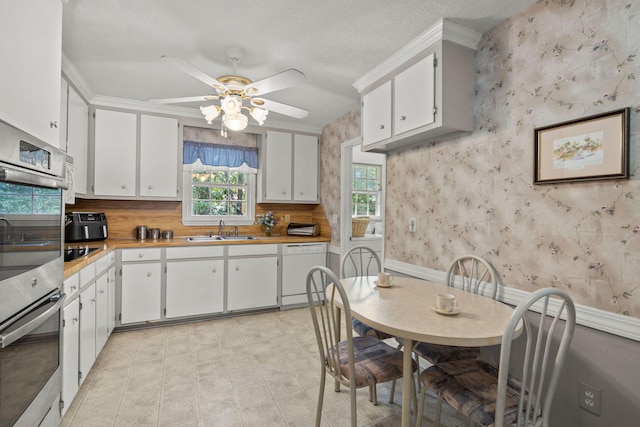 kitchen with white dishwasher, white cabinets, sink, a textured ceiling, and double oven