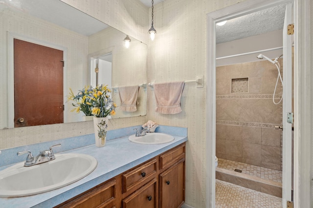 bathroom featuring tile patterned flooring, vanity, a tile shower, and a textured ceiling