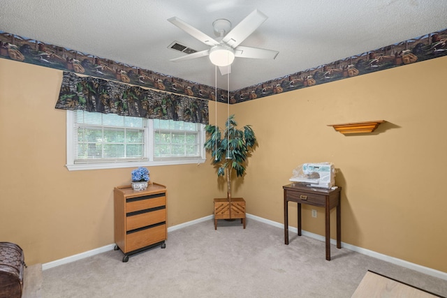 living area with a textured ceiling, ceiling fan, and light carpet