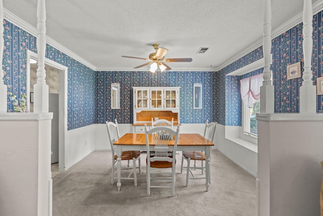 carpeted dining area with ceiling fan, a textured ceiling, and ornamental molding