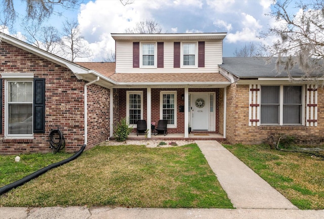 traditional home with roof with shingles, brick siding, a front lawn, and a porch