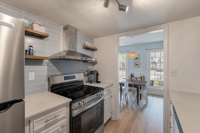 kitchen featuring white cabinets, stainless steel appliances, wall chimney range hood, open shelves, and backsplash