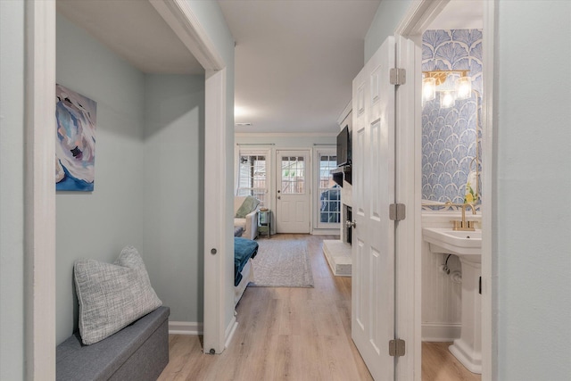 corridor with crown molding, light wood-style flooring, and baseboards