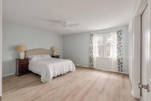 bedroom with a ceiling fan, visible vents, baseboards, and wood finished floors