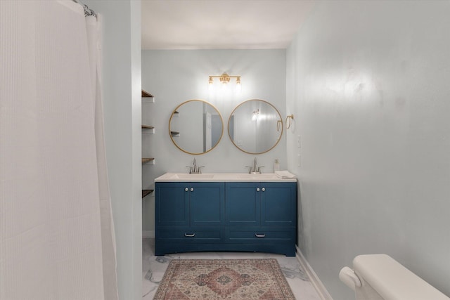 bathroom featuring marble finish floor, double vanity, a sink, and toilet