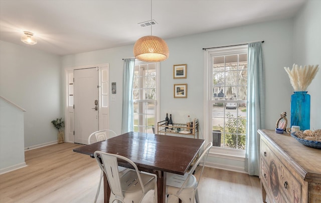 dining room with a healthy amount of sunlight, light wood-style flooring, visible vents, and baseboards