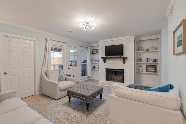 living room with ornamental molding, a fireplace, visible vents, and light wood-style floors