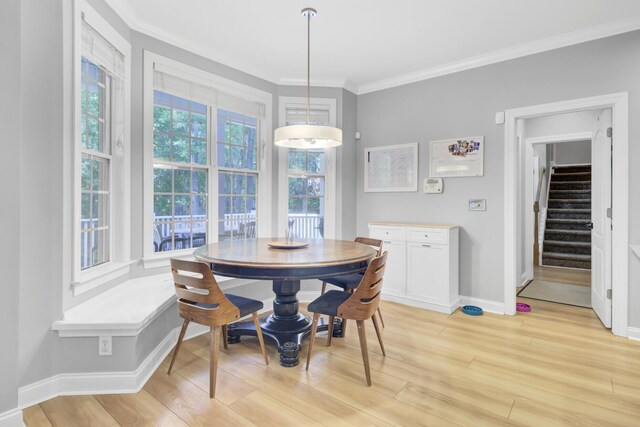 dining space featuring stairway, crown molding, light wood-style floors, baseboards, and breakfast area