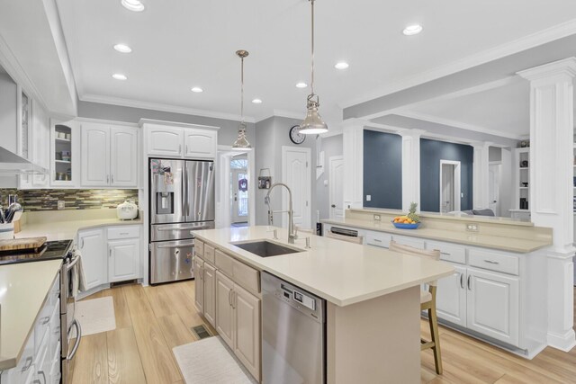 kitchen featuring stainless steel appliances, decorative columns, a sink, a kitchen island with sink, and recessed lighting