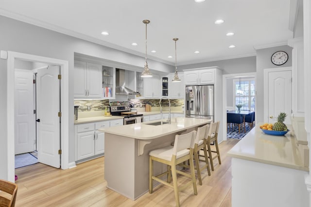 kitchen with a sink, stainless steel appliances, wall chimney exhaust hood, a kitchen island with sink, and tasteful backsplash