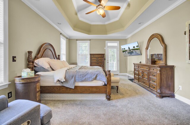 bedroom featuring a tray ceiling, carpet, crown molding, baseboards, and ceiling fan