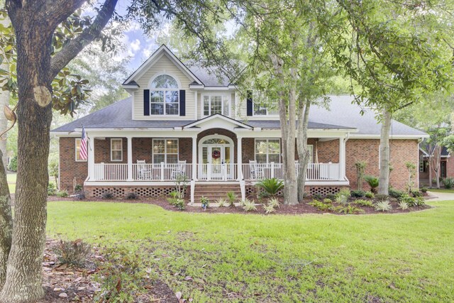traditional-style home with covered porch, a front lawn, and brick siding