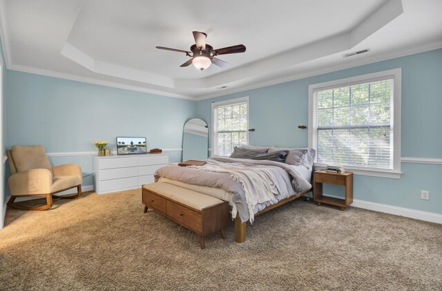bedroom with a tray ceiling, carpet, baseboards, ornamental molding, and a ceiling fan