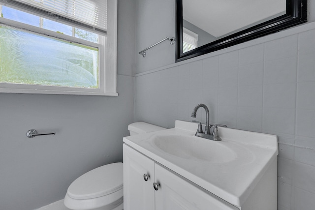 bathroom with vanity, tile walls, and toilet