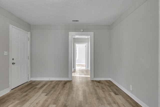 spare room with light wood-type flooring and a textured ceiling