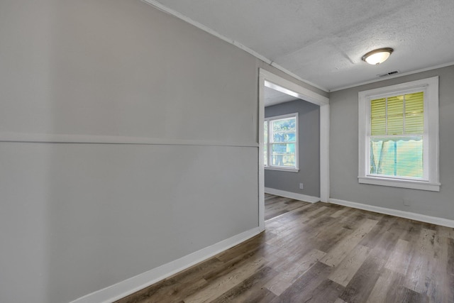 unfurnished room with ornamental molding, a healthy amount of sunlight, a textured ceiling, and hardwood / wood-style flooring